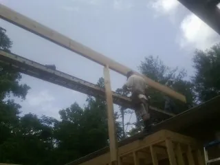 Carpenter setting a ridge beam over a new addition frame — Ice Dam Removal by Roofing Brothers in Kernersville