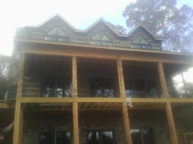 Dormers and porch framing on a large log home under construction — Roof Coating work by our crew in Kernersville