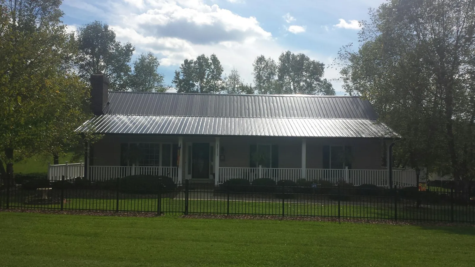 Gray metal roof on a brick ranch with a full width front porch — Gutter Guard Installation work by our crew in Kernersville