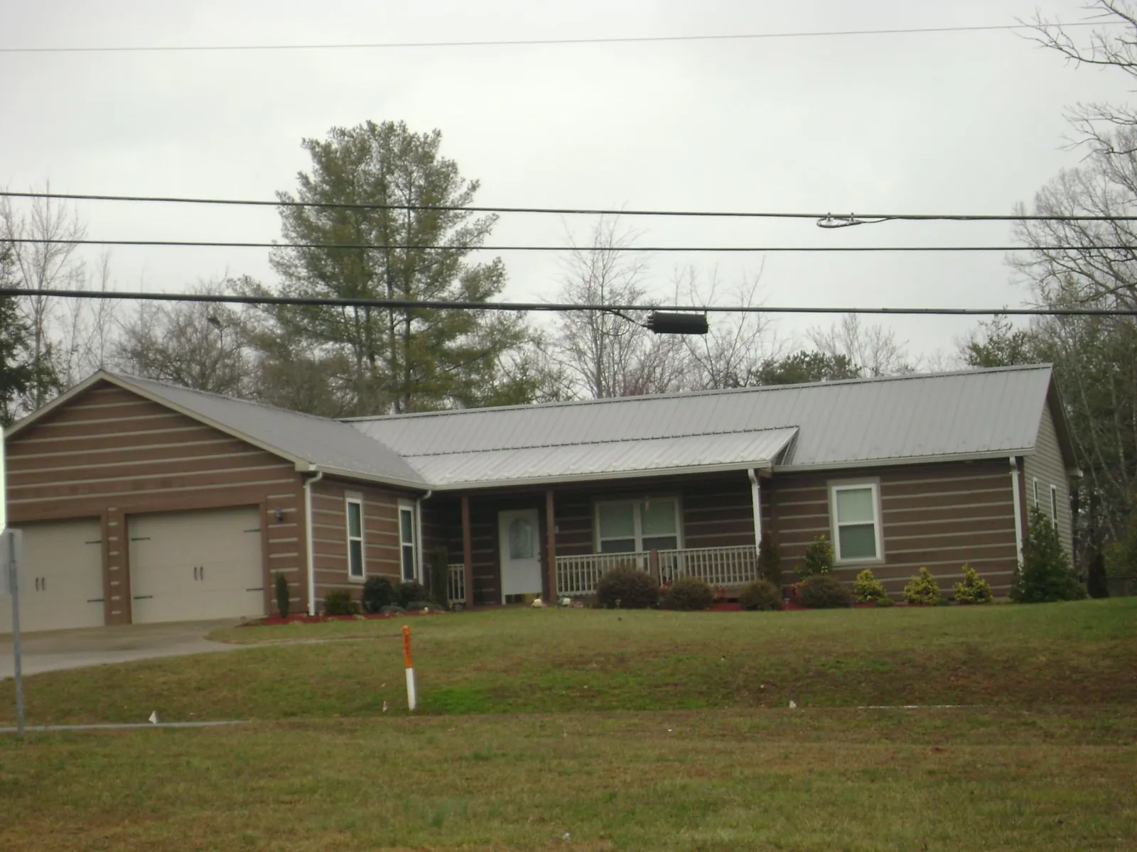 Gray metal roof on a log sided ranch home with a front porch in Kernersville