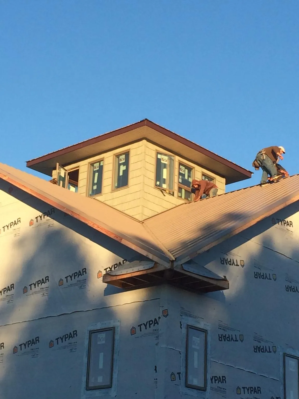 Roofers working around a rooftop cupola on a new metal roof at sunset — Roof Waterproofing in Kernersville by Roofing Brothers